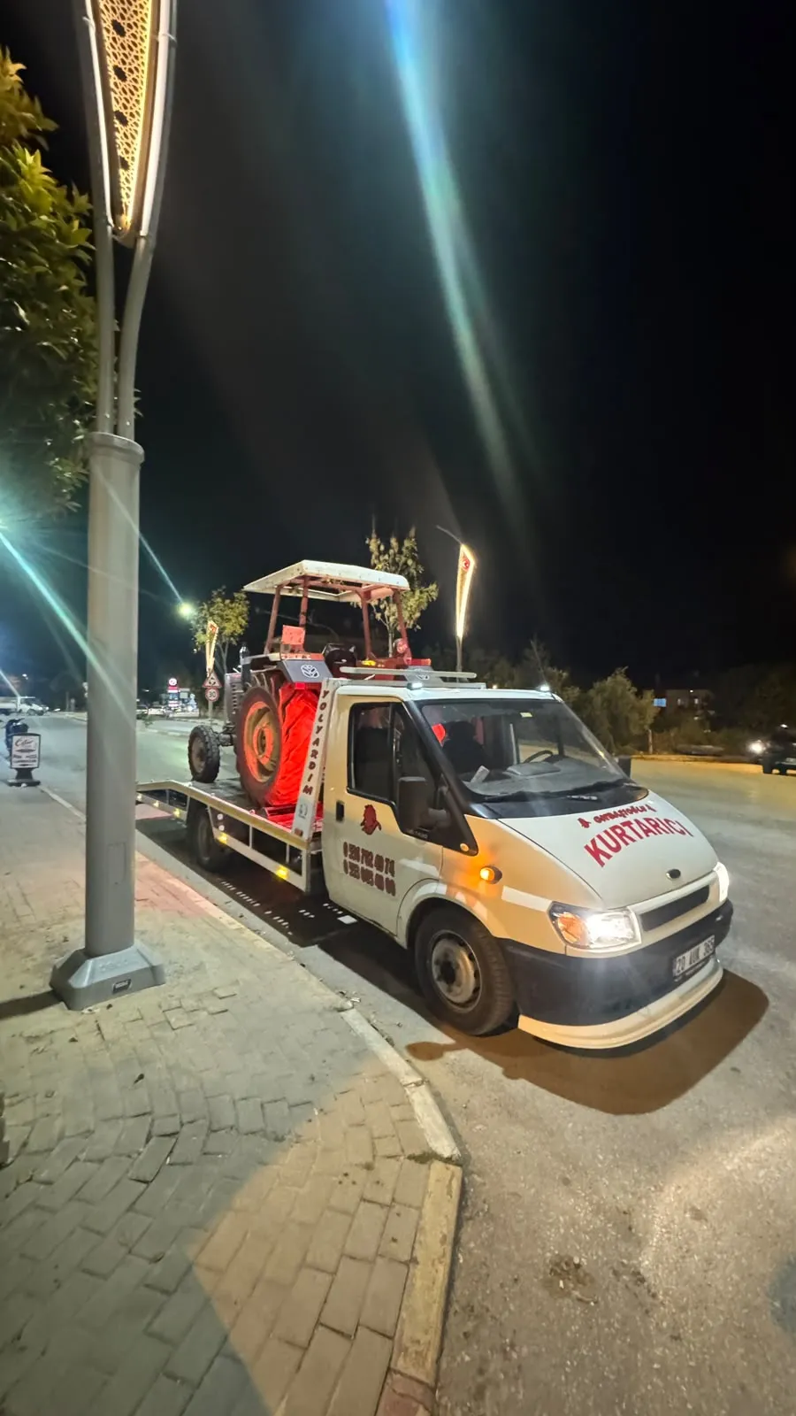 Şehir içinde sokak lambası altında traktör taşıyan çekici
